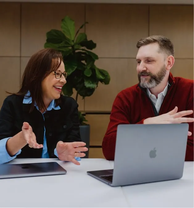 two people talking in while looking at a laptop